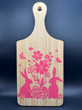 Wooden cutting board with pink floral and bunny designs on a dark blue background