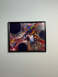 Abstract painting with colorful swirls in a black frame on a light gray wall